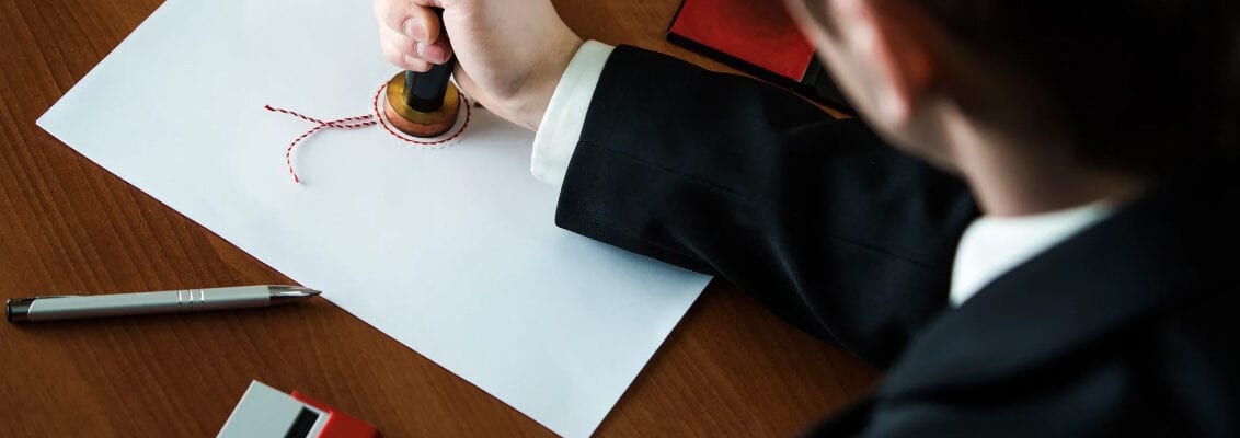 A man in a suit writing on paper.