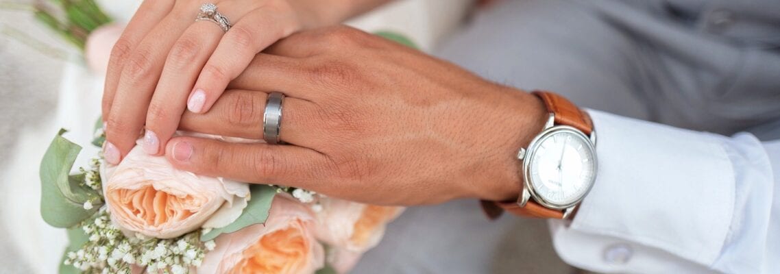 A man and woman holding hands with wedding rings on.