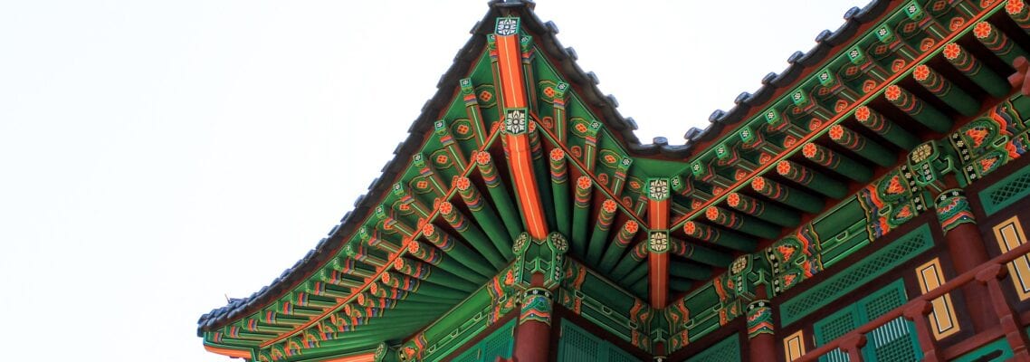 A building with green and red roof is seen from below.