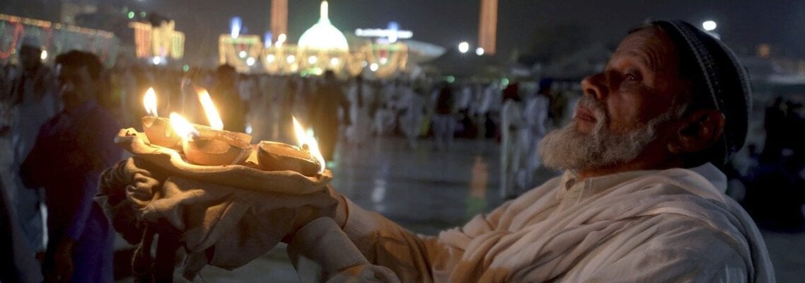 A man holding a candle in front of a crowd.