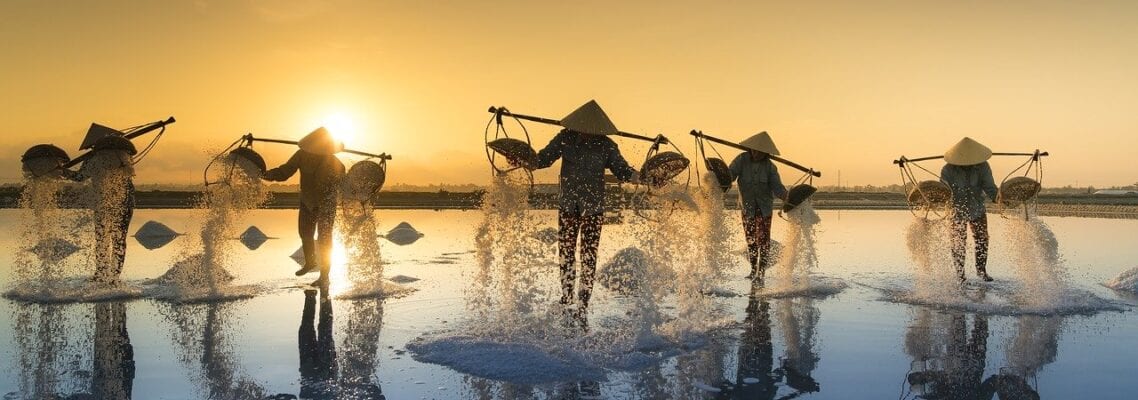 A group of people standing in water holding sticks.