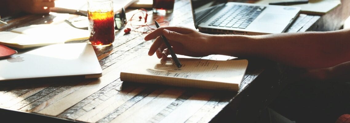 A person is sitting at a table with papers and coffee.