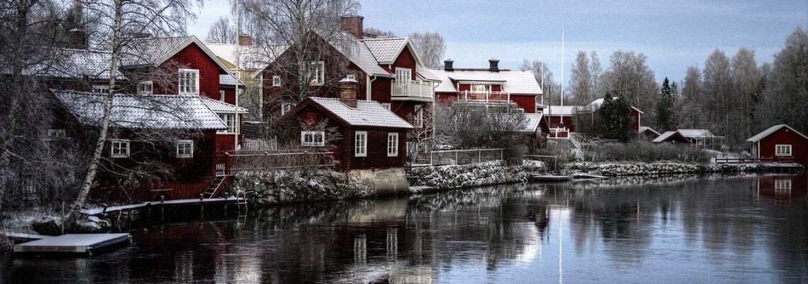 A river with houses on it and snow on the ground.