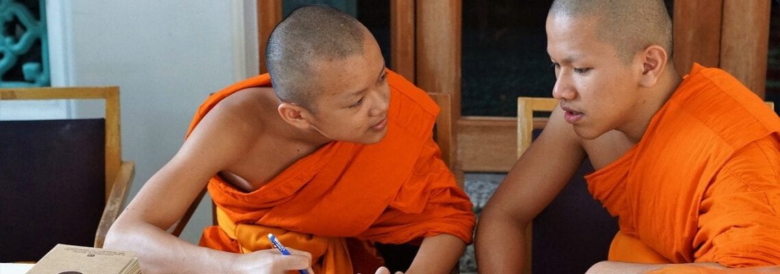 Two young monks are sitting at a table