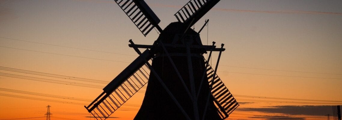 A windmill is silhouetted against the sunset.