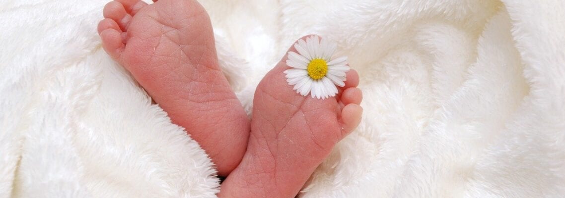 A baby 's feet with a flower in it.