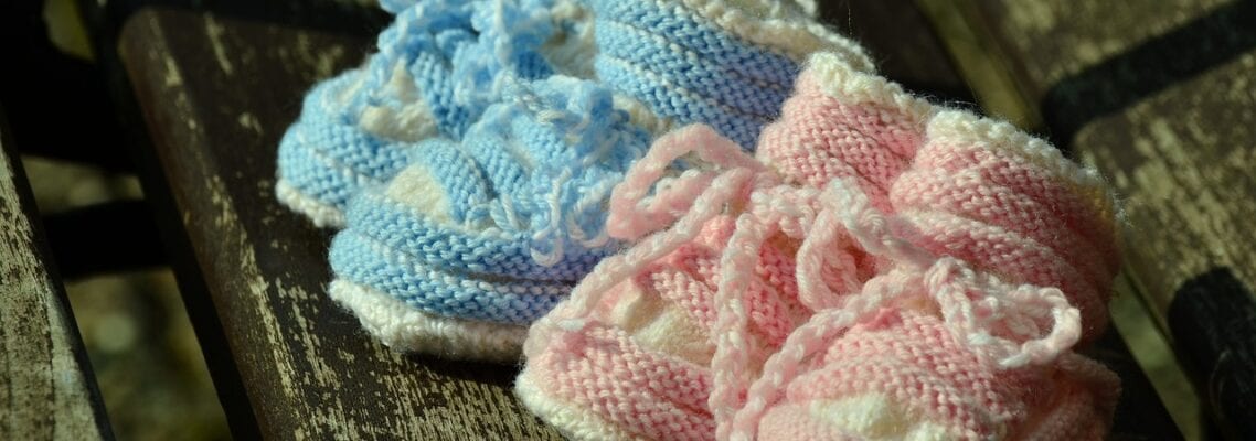 Two baby booties are sitting on a wooden table.