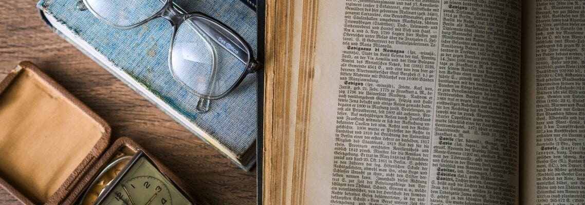 A book with glasses and an alarm clock on it