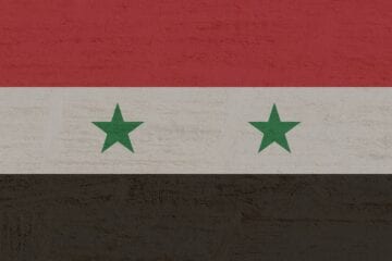 A flag of syria with two stars on it.