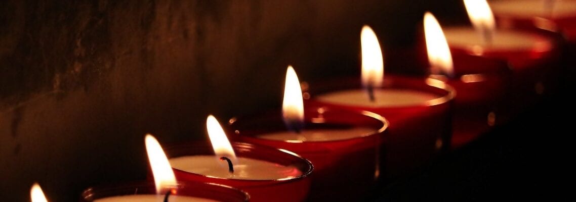 A row of candles lit in front of a dark background.