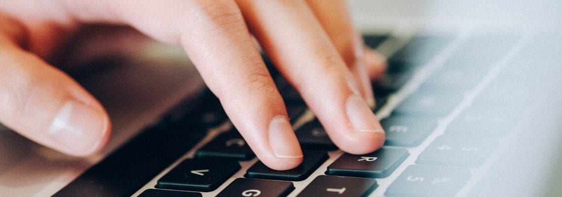 A person typing on a laptop keyboard.