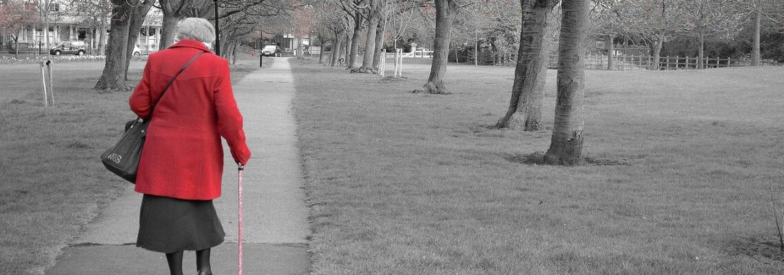 A woman in red coat walking down the sidewalk.