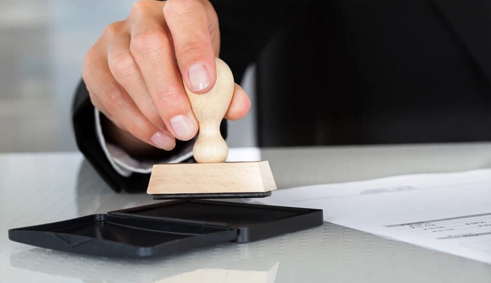 A person is using a rubber stamp on a piece of paper.