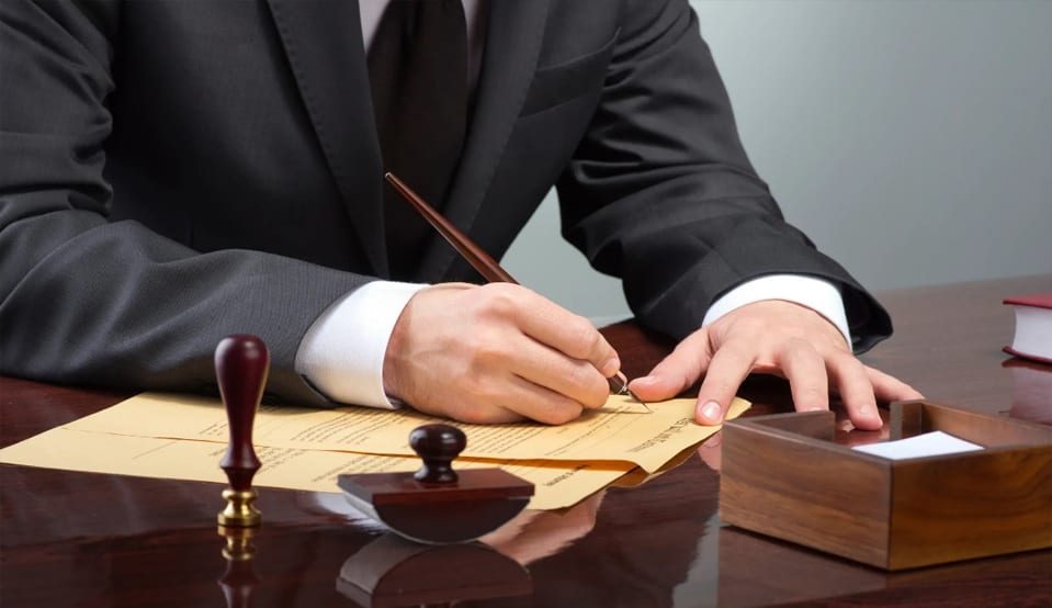 A man in suit and tie writing on paper.